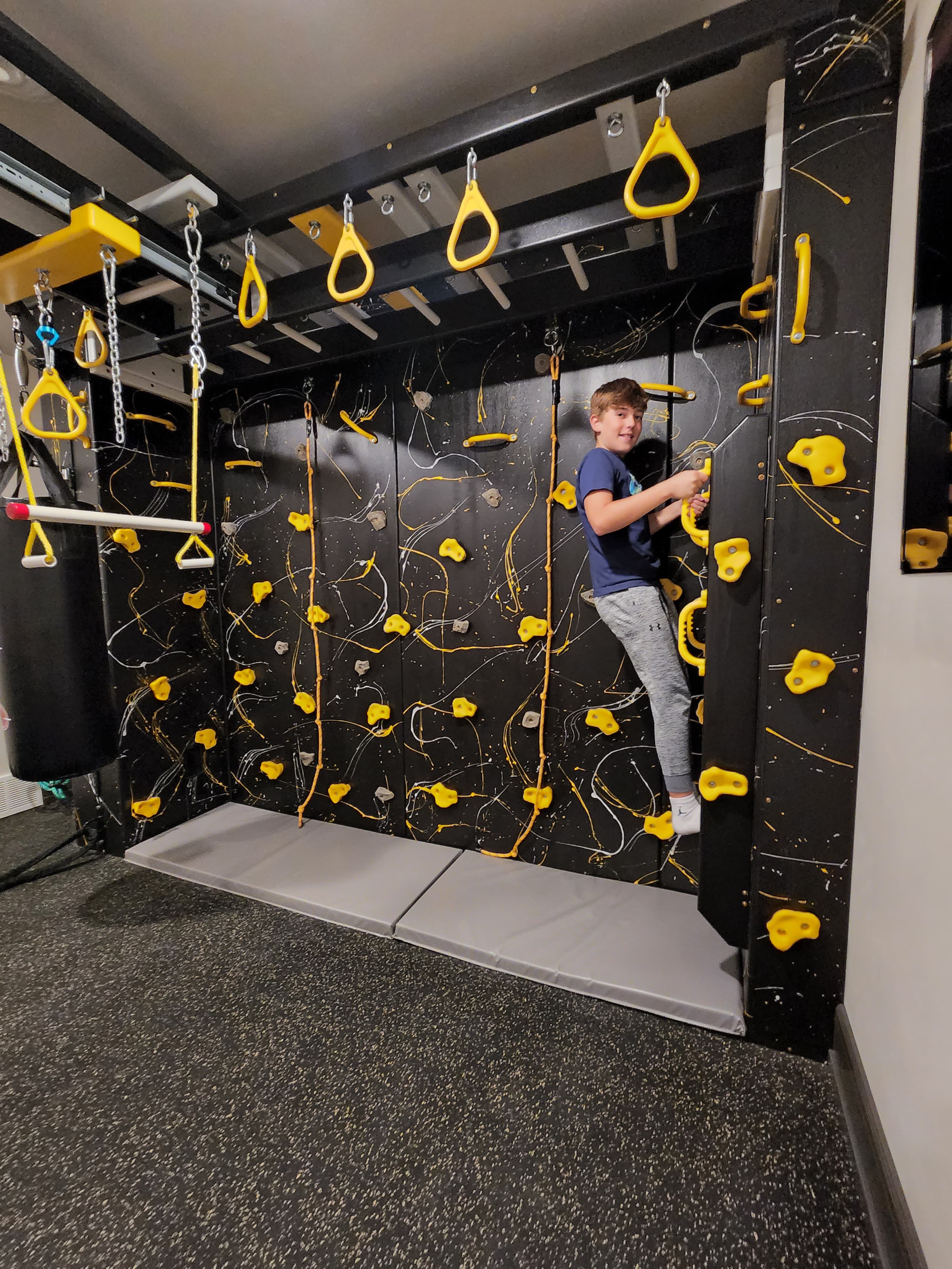 Child climbing in premium residential dark-theme sensory gym