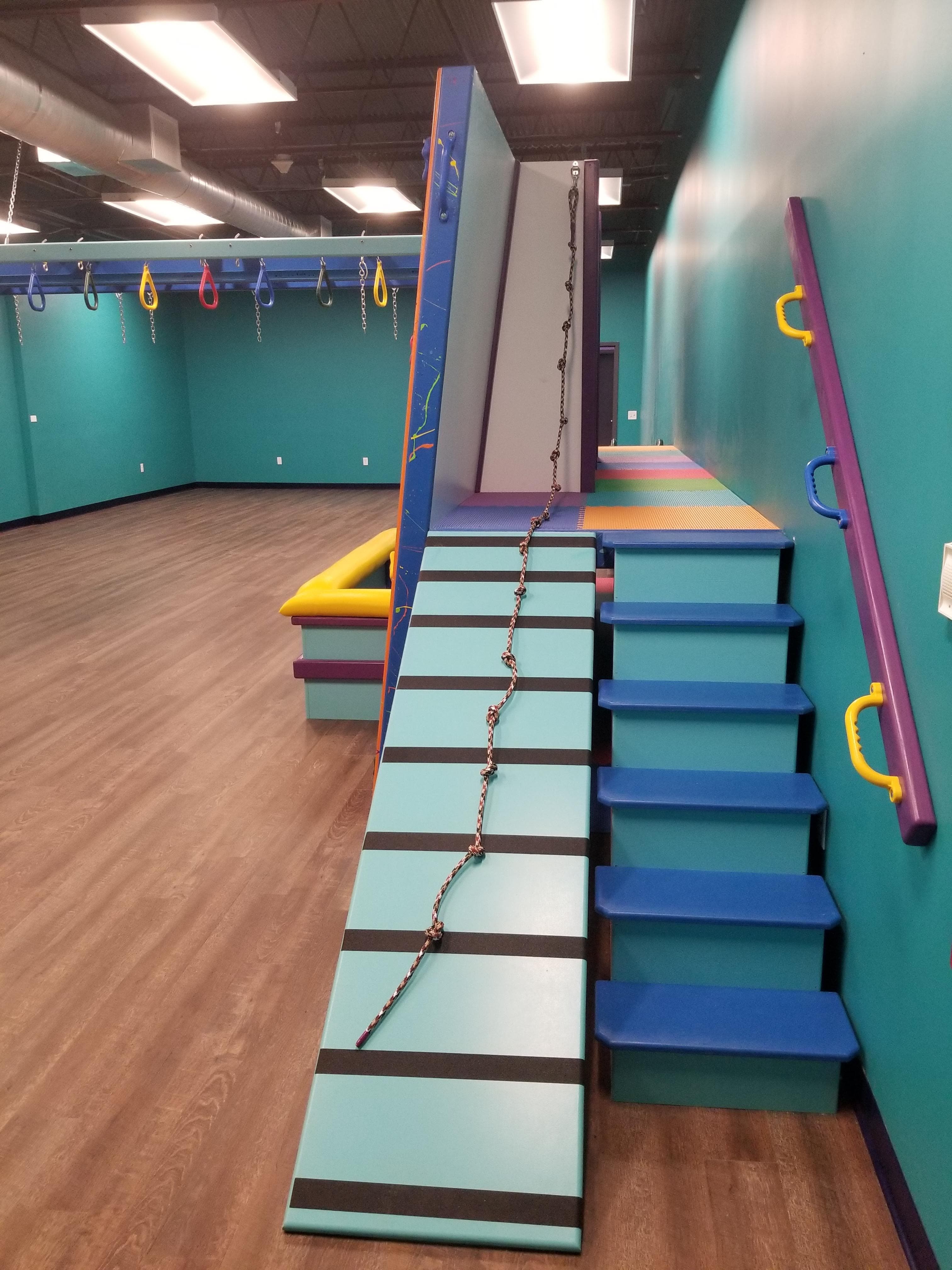 Structured sensory gym zones with climbing wall and swing areas