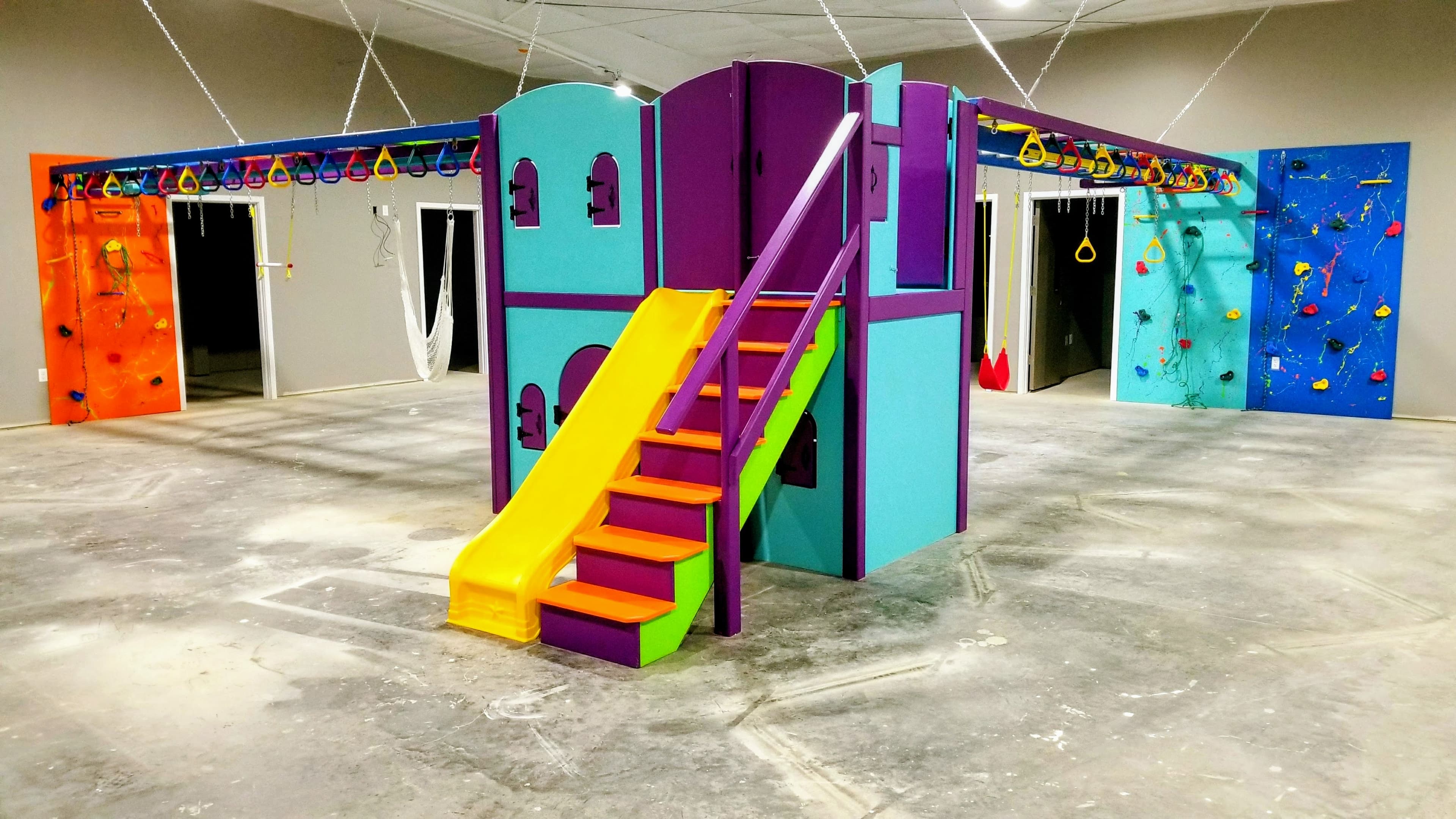 Residential gym with castle playhouse structure, yellow slide, and climbing walls